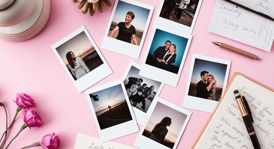 Polaroid photos and flowers laid out on a pink desk
